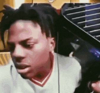 a man with dreadlocks is sitting in front of a piano and making a funny face .