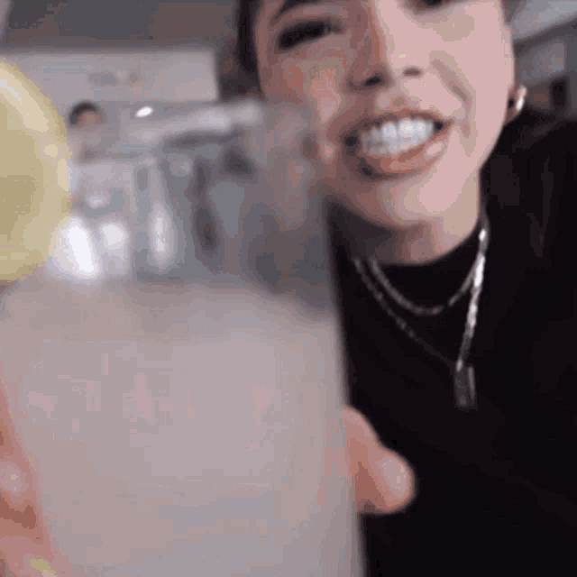 a woman is drinking a glass of lemonade with a slice of lemon in it .