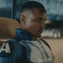 a close up of a man wearing a blue sweater and a white shirt