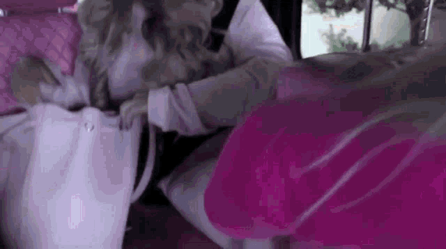 a woman is sitting in the back seat of a car looking into her purse .