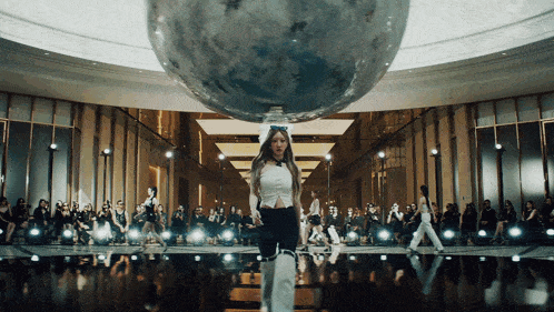 a woman in a white top stands in front of a globe