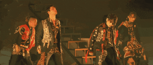 a group of men in kimonos are dancing on a stage in a dark room