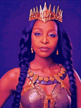 a woman wearing a crown and a braided necklace is standing in front of a purple background .