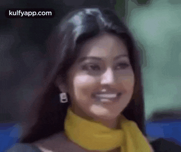 a woman wearing a yellow scarf and earrings is smiling and looking at the camera .
