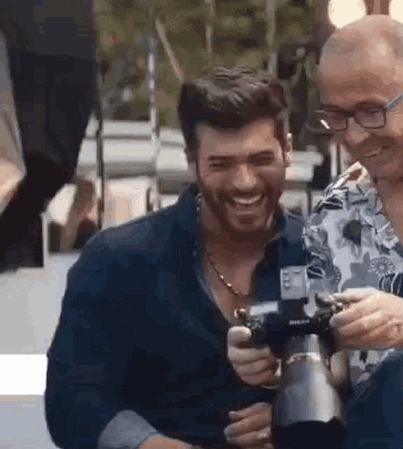 a man is holding a camera while another man laughs .