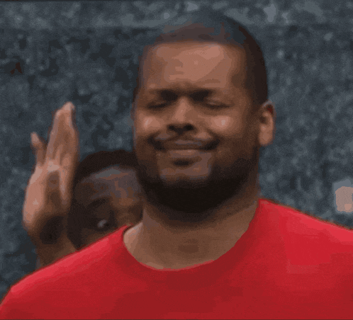 a man in a red shirt is smiling and making a face