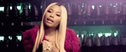 a woman in a pink fur coat is holding a bunch of money and playing cards .