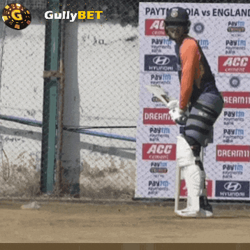 a cricket player stands in front of a wall that says gullybet on it