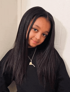 a young girl wearing a black sweater and a necklace with a key on it .