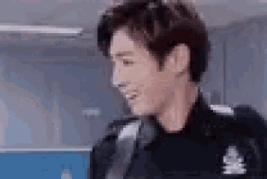 a man in a police uniform is smiling and looking at the camera in a room .