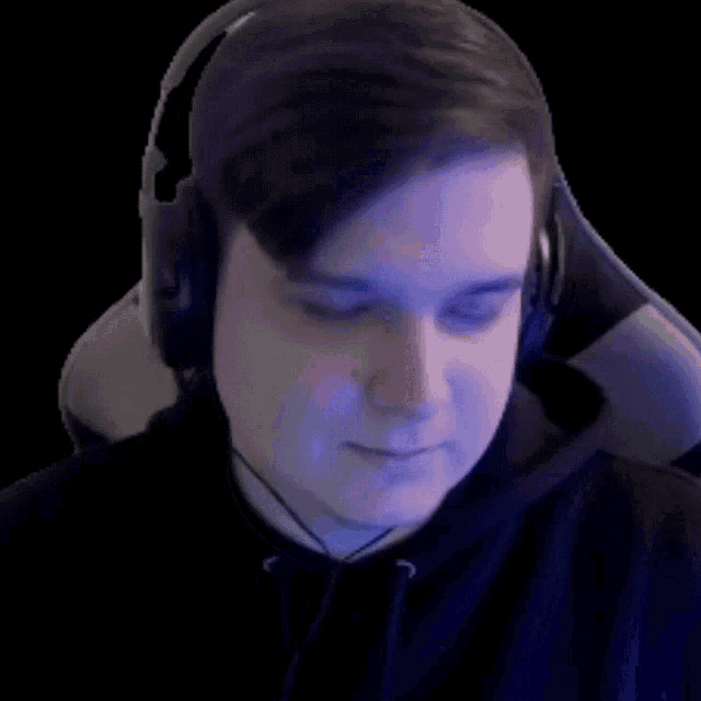 a man wearing headphones and a black shirt looks at the camera