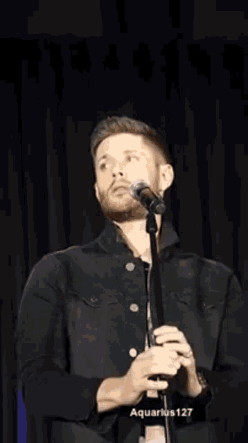 a man is singing into a microphone on a stage .