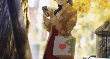 a woman is holding a bag with a heart on it while looking at her phone .