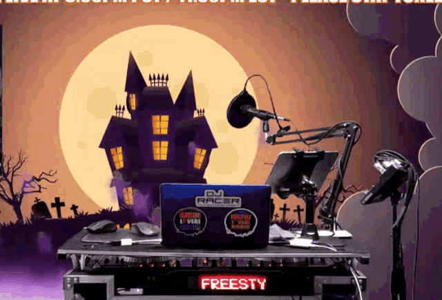 a dj racer laptop is sitting on a table with a haunted house in the background
