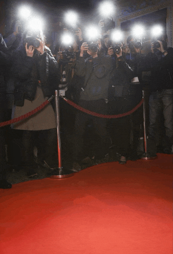 a crowd of people are standing around a red carpet