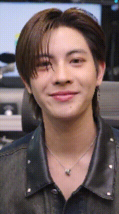 a close up of a man wearing a necklace and a leather jacket .