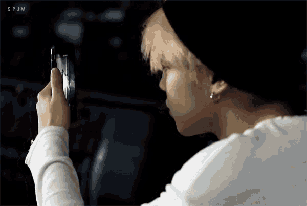 a person is taking a picture with a cell phone and the letters spjm are visible
