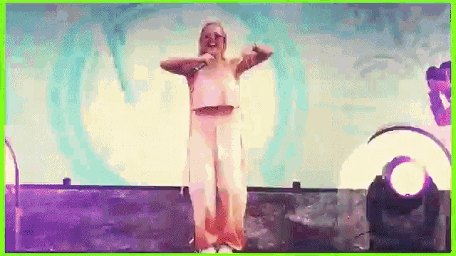 a woman is singing into a microphone while dancing on a stage