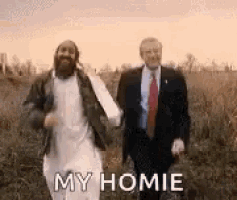a man in a suit and tie is walking with a man in a beard in a field .