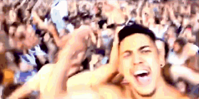 a shirtless man stands in front of a crowd with his mouth open