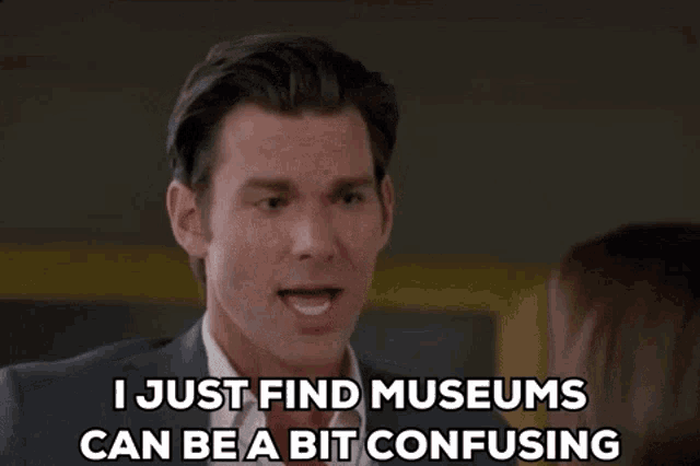 a man in a suit and tie is talking to a woman and says i just find museums can be a bit confusing