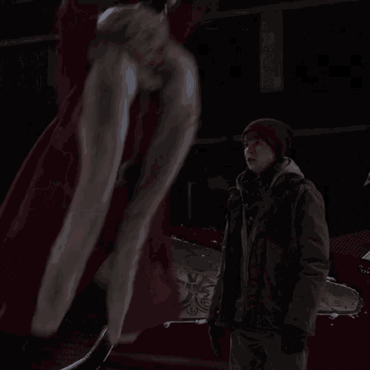 a cat wearing a red jacket is laying on the snow
