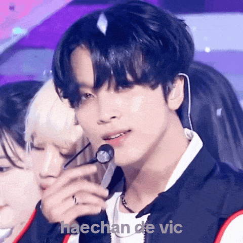 a close up of a man holding a microphone with the name haechan de vic written below him