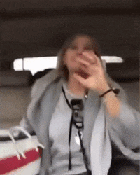 a woman is sitting in the back seat of a car covering her mouth with her hand