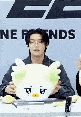 a man is holding a stuffed animal in front of a sign that says `` ne friends '' .