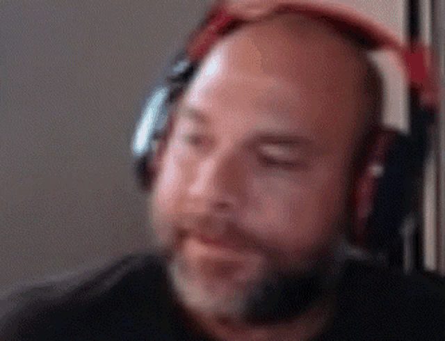 a bald man with a beard wearing headphones with his eyes closed .
