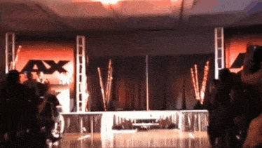 a crowd of people are gathered in front of a stage with a ax logo on it