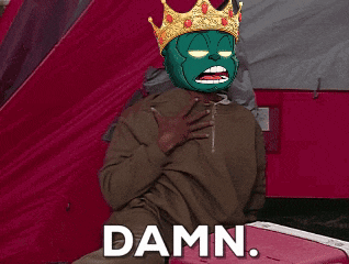 a man wearing a green mask and a gold crown is sitting next to a cooler that says damn