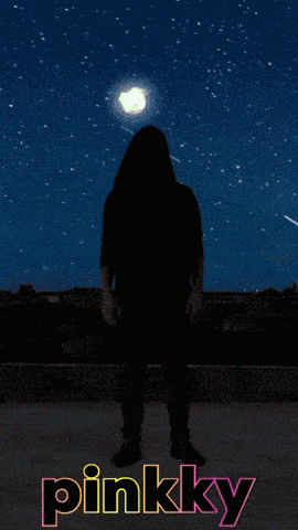 a woman stands in front of a pink sky