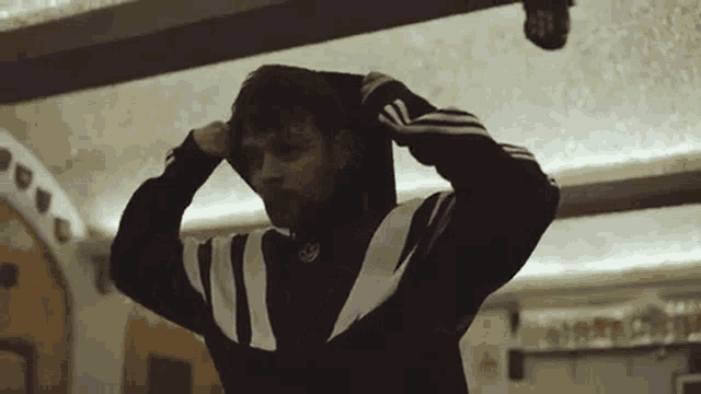 a man wearing a black and white adidas sweatshirt