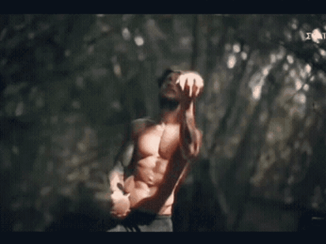 a man without a shirt is juggling balls in the woods