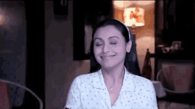 a woman is smiling with her eyes closed in a dark room .