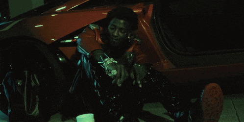 a man sits in front of a red car