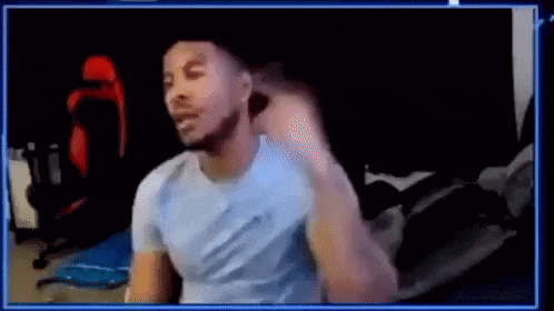a man in a blue shirt is sitting in front of a computer screen and making a funny face .