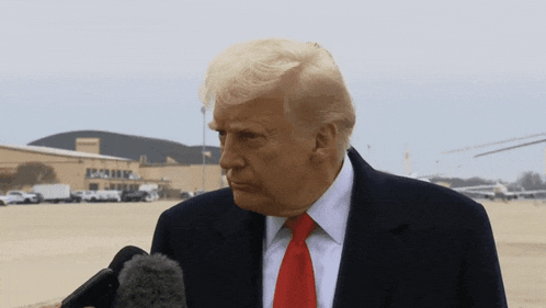 donald trump speaking into a microphone in front of a building that says seattle on it