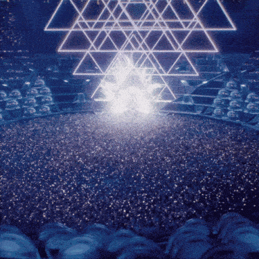 a crowd of people are gathered in a stadium with a pyramid in the background