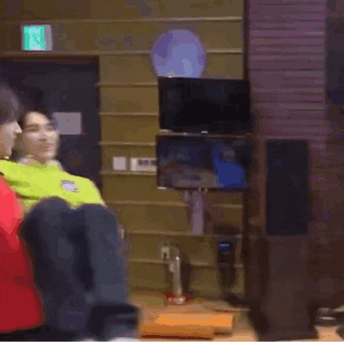 a man in a neon green sweater is carrying another man on his shoulders .