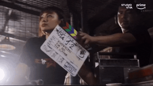 a woman is holding a clapper board that says 2014 1-2 on it