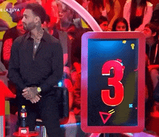 a man is sitting in front of a screen with the number three on it