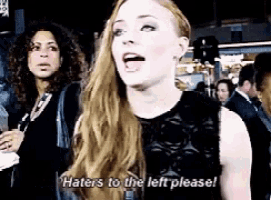 a woman is standing in a crowd and saying haters to the left please .