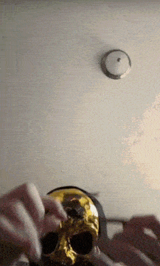 a person is holding a gold skull in their hands