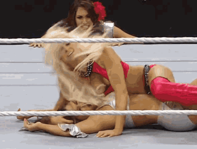 two women are wrestling in a ring and one of them is laying on the ground