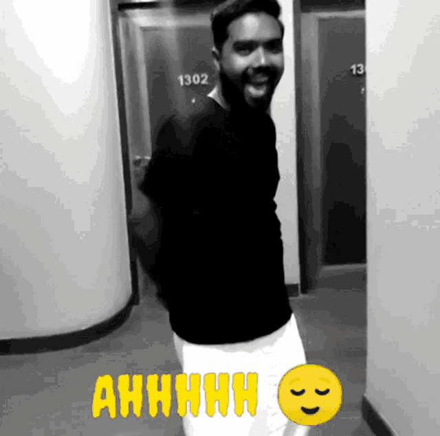 a man standing in a hallway with the number 1302 on the door behind him