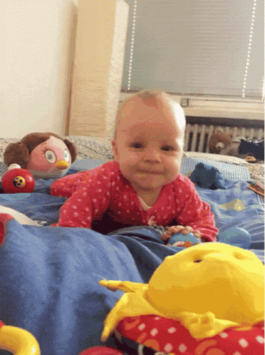 a baby is crawling on a bed with toys