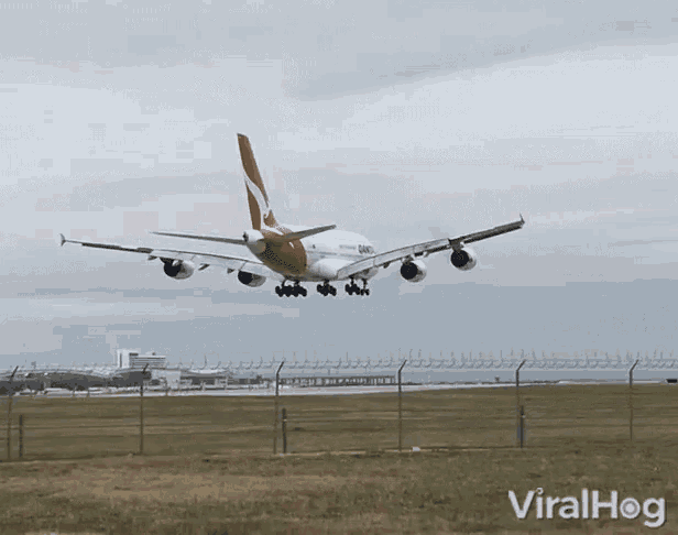 a red and white airplane is taking off from a runway with viralhog in the corner