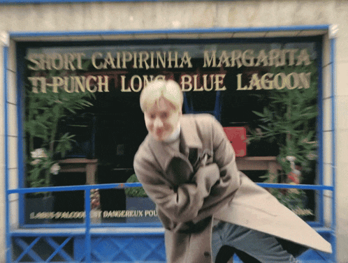 a man stands in front of a sign that says short caipirinha margarita ti-punch long blue lagoon